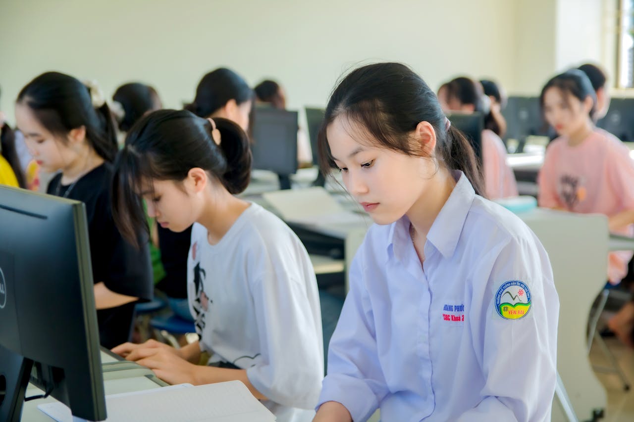 Young Asian women focused on studying in a university computer lab.