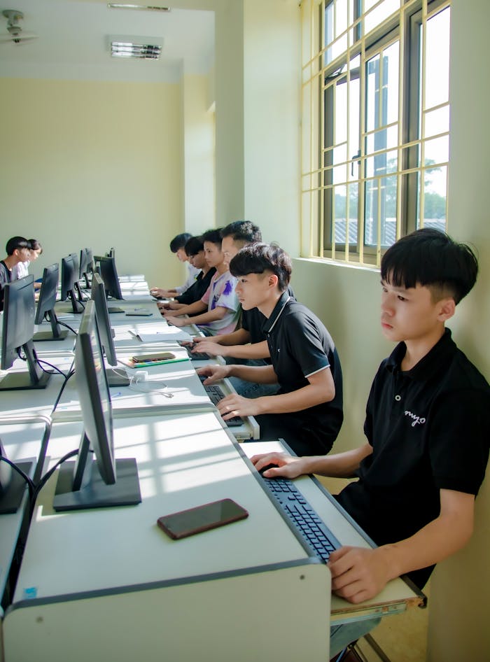 A group of male students working on computers in a classroom setting.